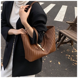 Detail shot of brown woven leather tote bag texture with beaded accessory charm