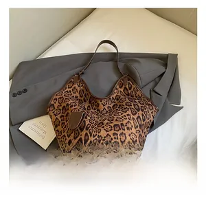 Close-up of leopard print canvas tote bag with brown leather trim on a grey blazer