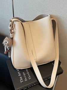Chic beige lychee leather bucket bag with an owl charm for daily commuting style