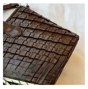 Close-up of brown woven leather texture with cross-stitch pattern on a stylish handbag