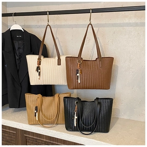 Close-up of four woven tote bags featuring beaded charms and leather shoulder straps