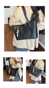 Detail of black woven leather tote bag featuring a stylish multi-colored bead pendant