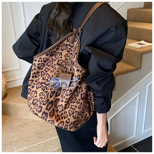 Detailed side view of leopard print tote bag with leather handles and glasses holder