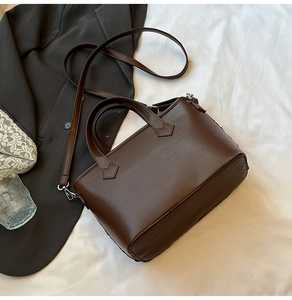 Detail view of a brown faux leather tote with reinforced handles and silver metal hardware