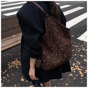Outdoor shot showing a large leopard print tote bag with brown leather straps and trim