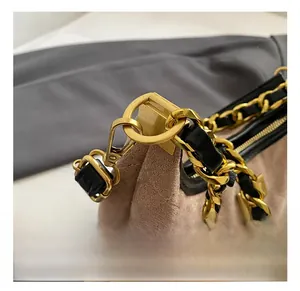 Détail du crochet doré et de la bandoulière en chaîne sur le sac en daim marron