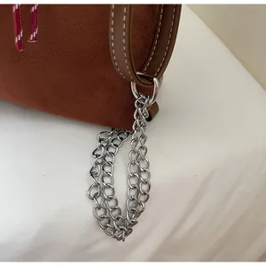 Detail of brown suede tote bag featuring silver multi-ring metal chain and leather handle