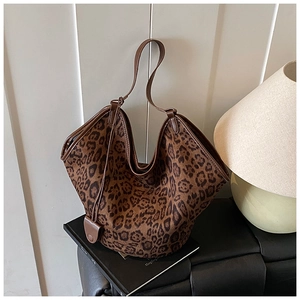 Detail of leopard print tote bag with brown leather handles on a lifestyle background