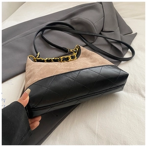 Dettaglio borsa beige in pelle scamosciata e nera con catena dorata e motivo a rombi