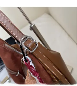 Detail of tan shoulder bag showing contrast stitching, adjustable strap, and silver buckle