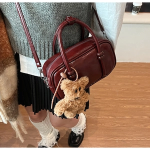 Deep red vintage Boston bag with plush bear charm worn by model in college style outfit