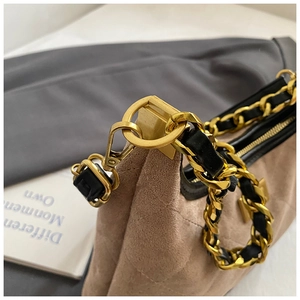 Dettaglio della chiusura a moschettone dorata e catena intrecciata su borsa in camoscio