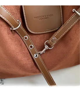 Close-up of caramel suede tote bag with silver polished hardware and embossed logo