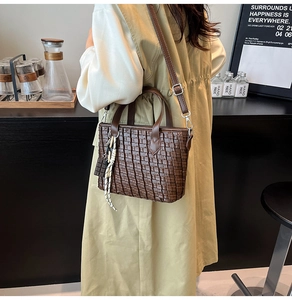 Detailed shot of dark brown woven tote bag with adjustable strap and novelty charm
