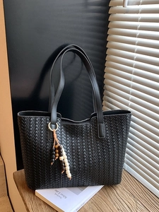 Large black woven tote bag with wooden bead tassel charm in natural light