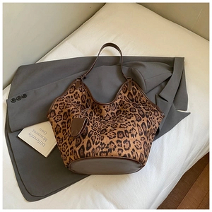 Detailed top view of large leopard print tote bag with brown leather trim on white surface
