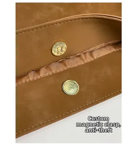 Dettaglio della chiusura magnetica dorata sulla borsa tote in pelle marrone di sicurezza