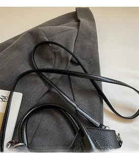Detail of black lychee grain leather bucket bag with smooth adjustable shoulder strap