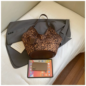 Detail of leopard print tote bag with brown leather strap on grey blazer and gadget props