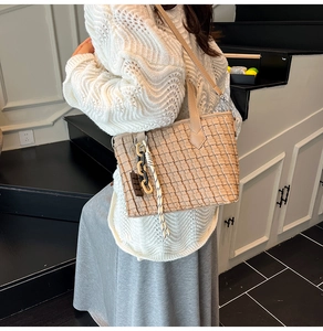Detail of beige woven tote bag showing fine square texture and decorative pendants