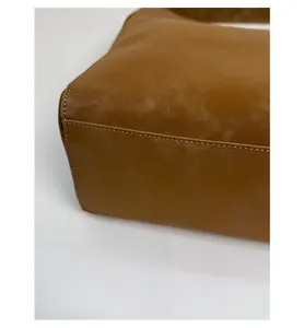 Dettaglio macro del fondo rinforzato e cuciture bianche su borsa tote in pelle scamosciata