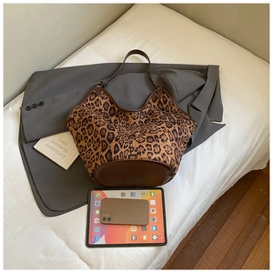 Detail view of large leopard print tote bag with brown leather trim and iPad for size comparison