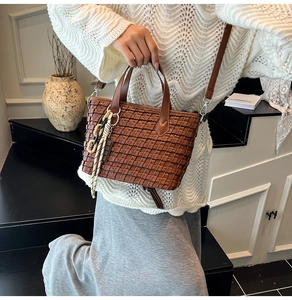 Detail of coffee brown woven PU leather bucket bag with decorative chain and strap