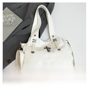 Close-up of white glossy leather tote bag with metallic cross detail and side pocket