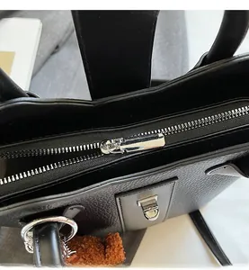 Close-up of smooth silver zipper and textured black lychee leather on bucket bag