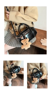 Dettaglio della mini borsa bowling nera lucida con un dolce ciondolo orsetto marrone