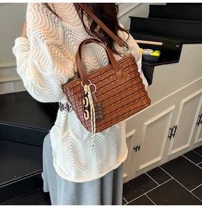 Detail of dark caramel woven bucket bag with creative chocolate charm and chain