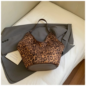 Detailed close-up of leopard print tote bag featuring brown faux leather trim and sturdy base