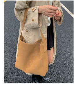 Vista street style di una grande borsa tote kaki in ecopelle opaca con ampia tracolla comoda