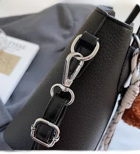 Detailed macro view of silver metal hooks and buckle on black lychee grain leather bag