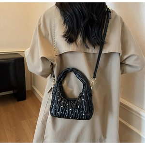 Detail showing the pleated hobo bag with rhinestone embellishments on a beige trench coat