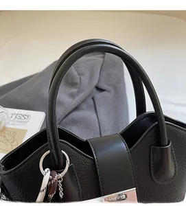 Detailed shot of black lychee leather bucket bag with silver metal buckle and woven charm