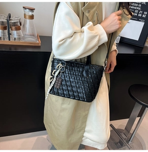 Detail of a black woven handbag featuring unique knot and chocolate charms for women