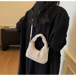 Close-up of pleated beige underarm bag with rhinestone details on a female model