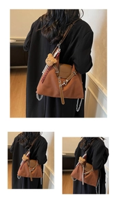 Detail of brown canvas tote bag with leather flap, metal chain, and cute bear charm