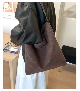 Dettaglio della borsa tote in pelle scamosciata marrone scuro con capienza ampia e tracolla