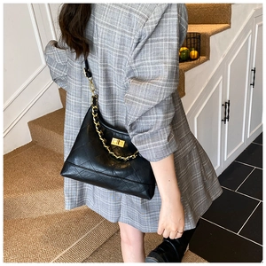 Détail du sac bandoulière noir matelassé avec chaîne dorée et fermoir rotatif