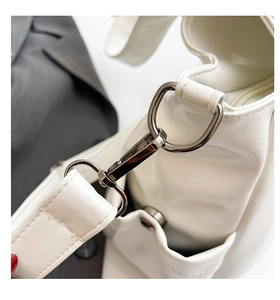 Detail of gunmetal D-ring and lobster clasp on a white faux leather tote bag