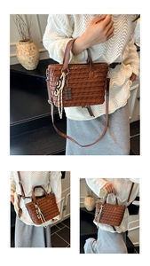 Detail view of a brown woven handbag with chocolate charm and black chain decoration