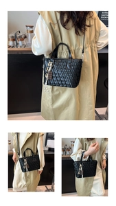 Detail of black woven tote bag featuring glossy finish and chocolate-shaped charm detail