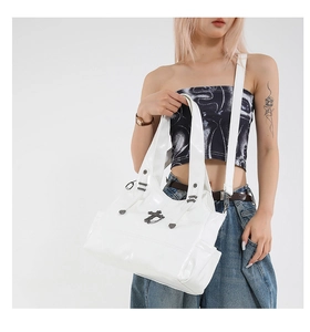 Detail of white glossy tote bag with metal cross charms and rivet hardware accents
