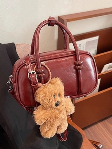 Vintage burgundy leather bowling bag with plush bear charm and adjustable shoulder strap