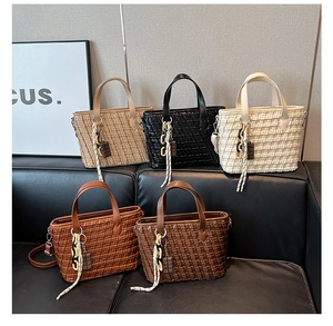 Detailed view of five woven tote bags in khaki, black, cream, orange, and brown on a sofa