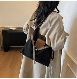 Detail of black suede tote bag with brown leather strap and fashion logo engraving