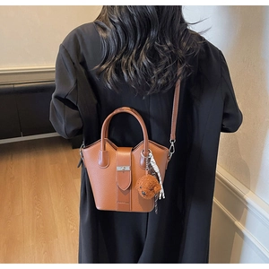 Detail of brown litchi pattern bucket bag with bear charm and polka dot scarf