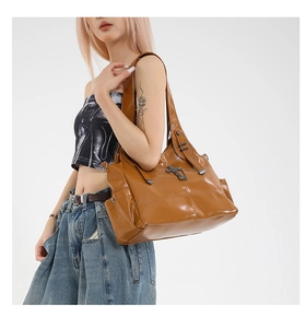 Brown leather tote bag featuring metal cross pendant and vintage buckle detail